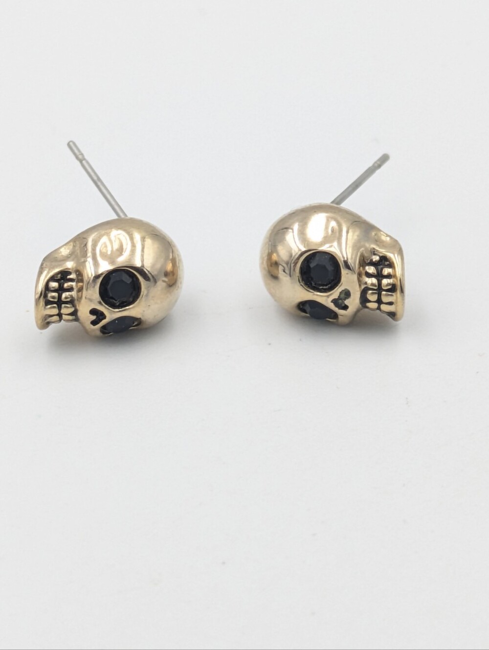 Gold tone skull earrings with black rhinestone eyes